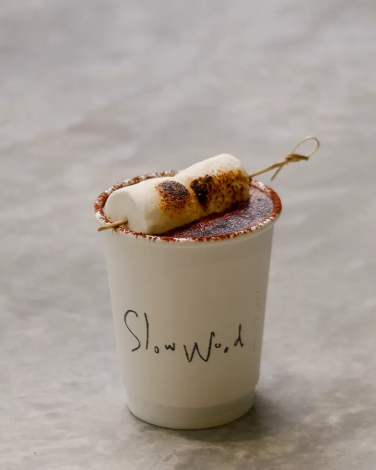 A chocolate drink topped with a toasted marshmallow skewer.