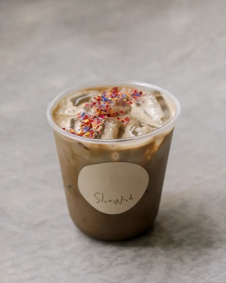 An iced hojicha latte topped with cream and sprinkles.