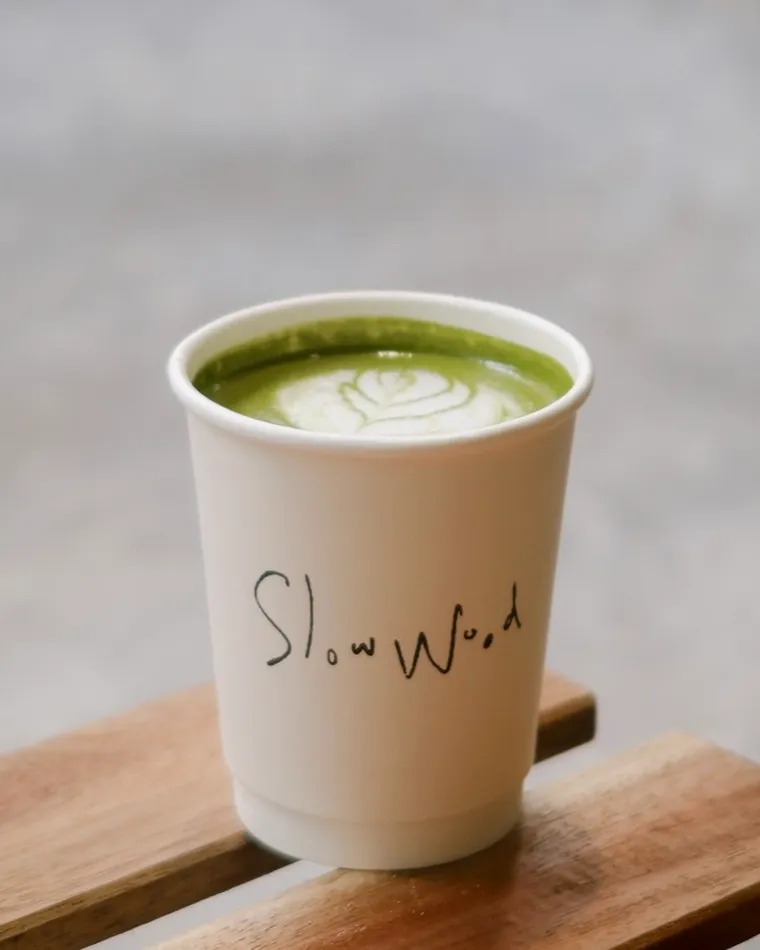 A matcha latte in a Slow Wood cup on a wooden ledge.
