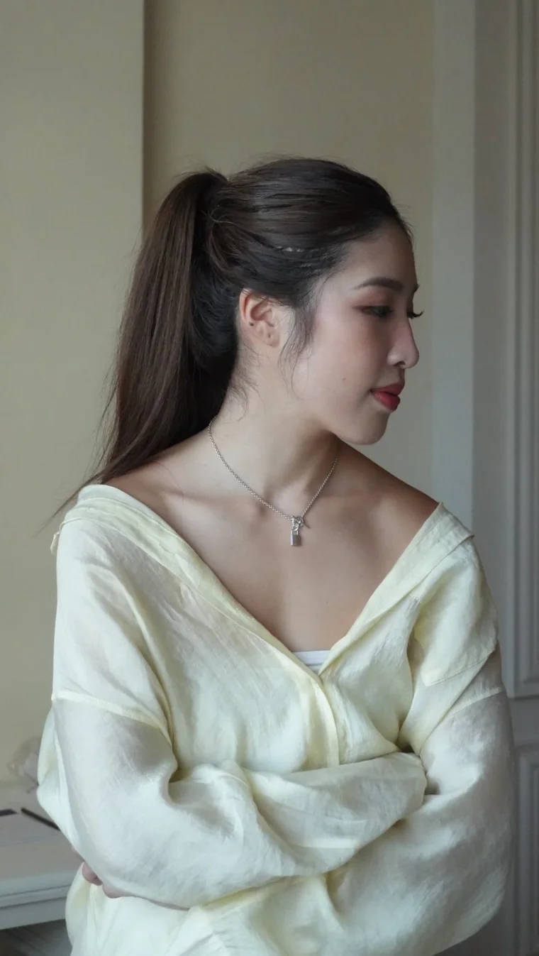 Crystal Lai in a cream knit, turned in profile.
