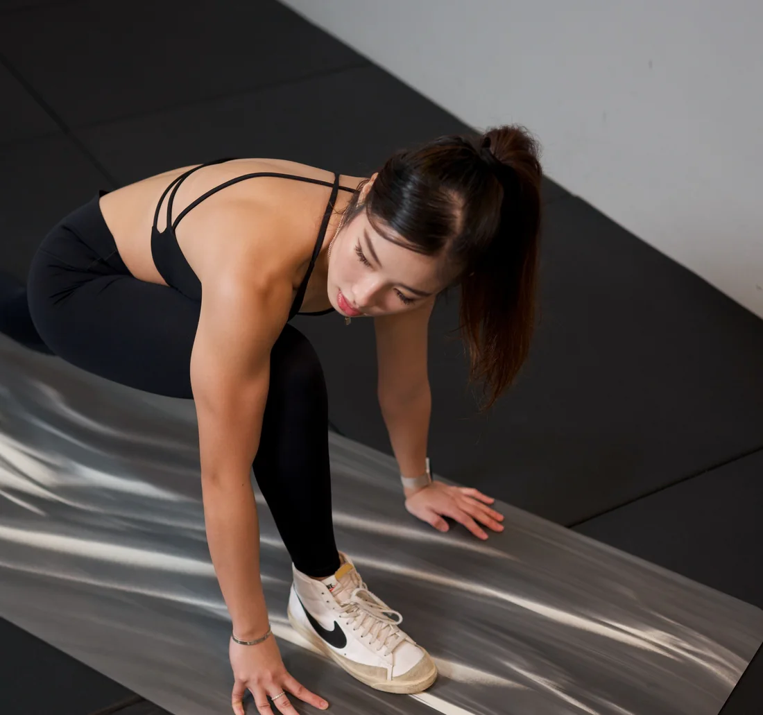 Crystal Lai stretching on a mat in the studio.